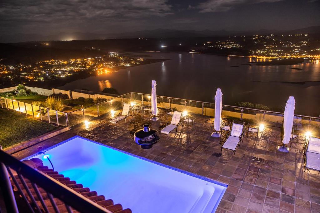 a swimming pool with chairs and a view of the water at Villa Castollini in Brenton-on-Sea