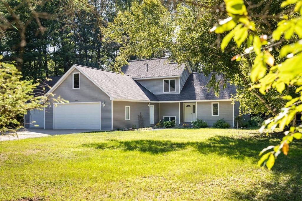 een huis met een garage en een grasveld bij Bissell Creek Woodside Cottage in Williamsburg