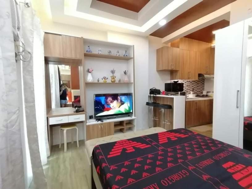 ein Schlafzimmer mit einem Bett und einem TV sowie eine Küche in der Unterkunft Antara Residentials and Condominium in Talisay