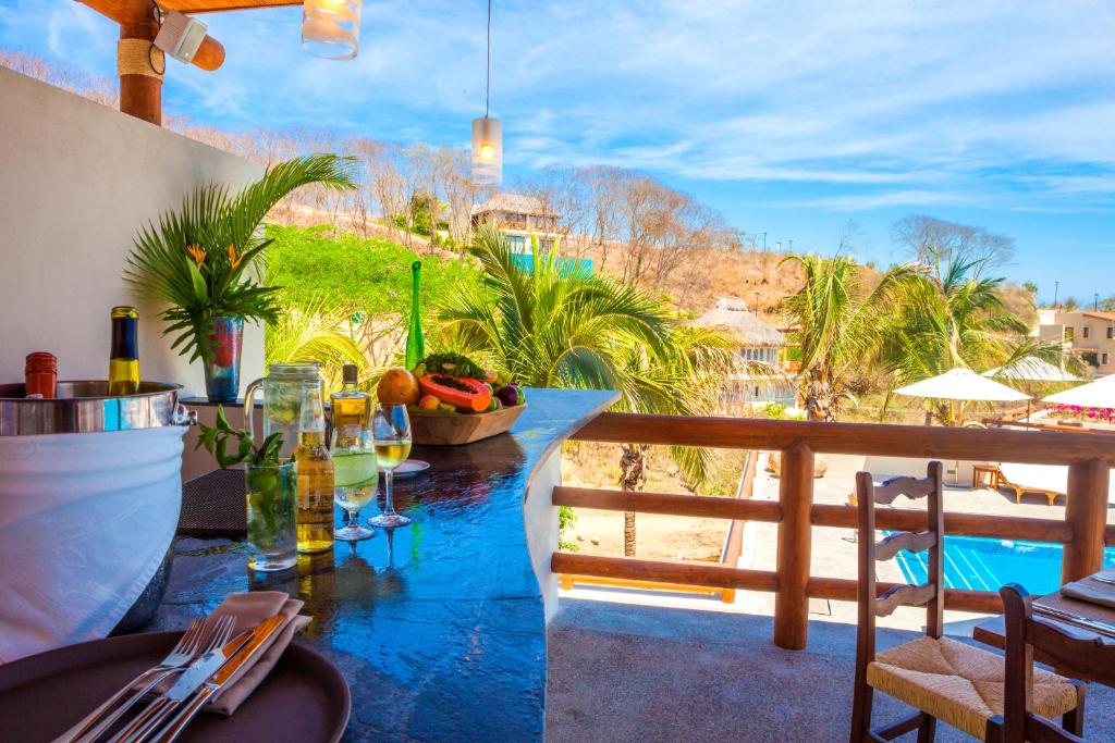 Balcony table with wine and appetizers overlooking pool, palm trees, and coastal landscape.