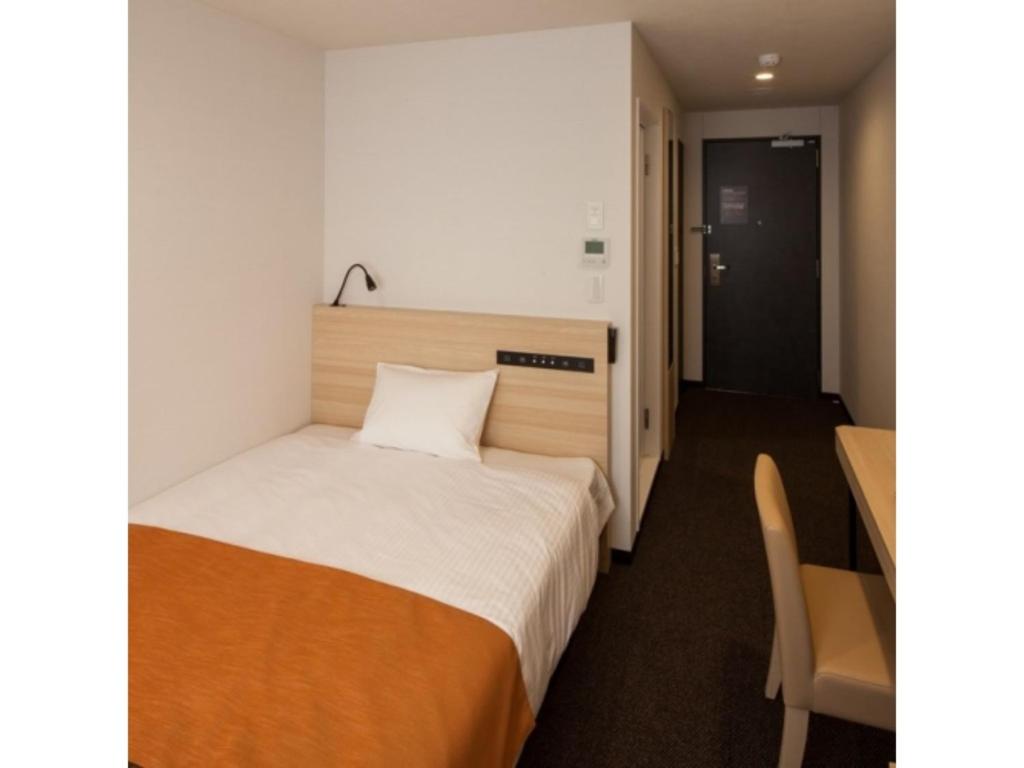 um pequeno quarto com uma cama e uma mesa em Y's Hotel Asahikawa Ekimae - Vacation STAY 65443v em Asahikawa