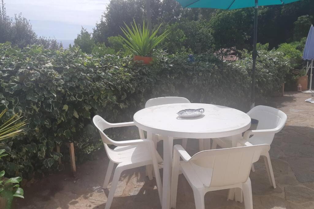 a white table with four chairs and an umbrella at La cacarinette in Rayol-Canadel-sur-Mer