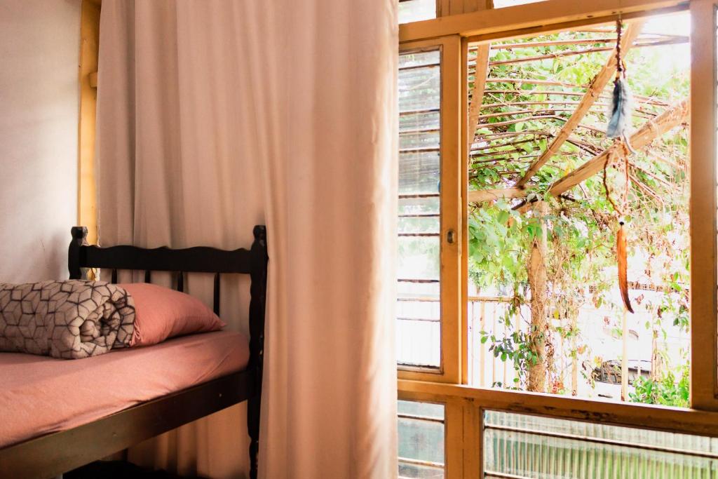 - une chambre avec un lit à côté d'une fenêtre dans l'établissement Cacau Hostel, à Goiânia