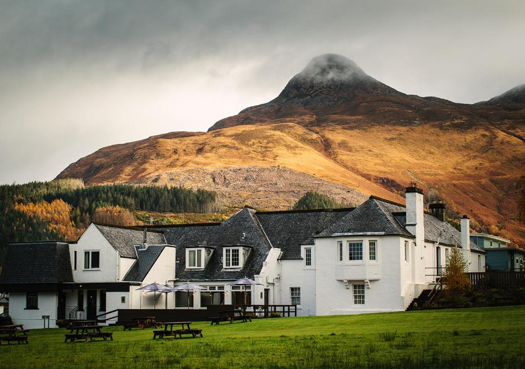 uma grande casa branca com uma montanha ao fundo em The Glencoe Inn em Glencoe