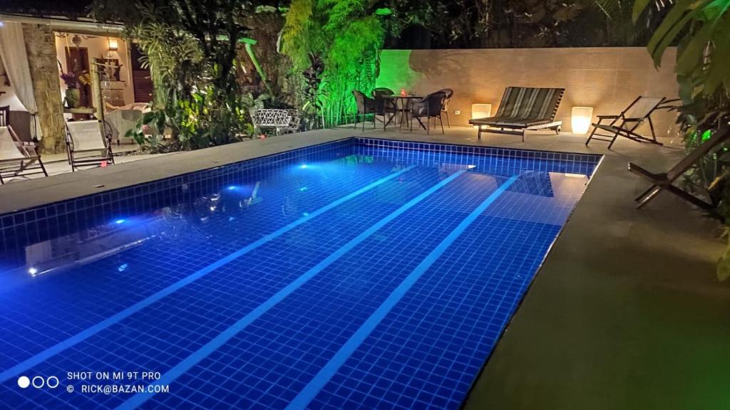 Eliconial Paraty Pousada في باراتي: حمام سباحة في الليل مع أضواء زرقاء