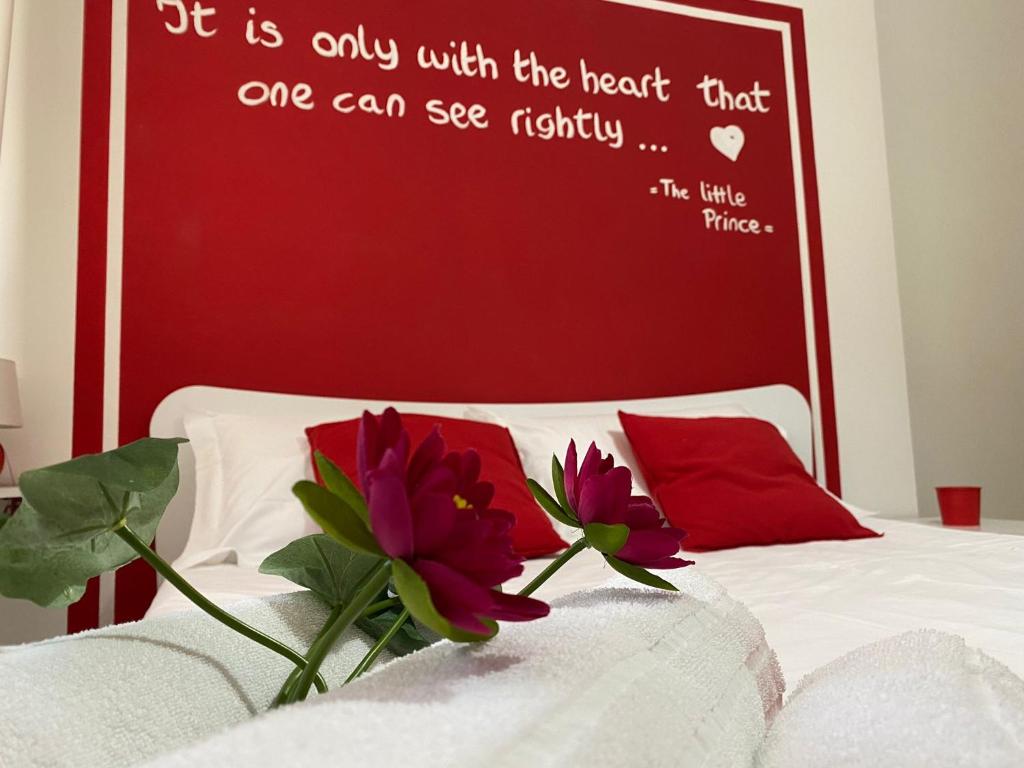 Una pared roja sobre una cama con dos flores. en Politeama Center, en Palermo