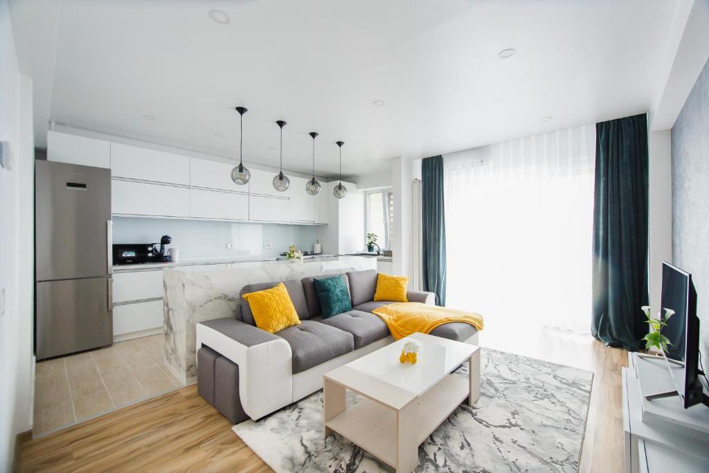 a living room with a gray couch and yellow pillows at Elegant & Spacious – Central Apartment in Oradea