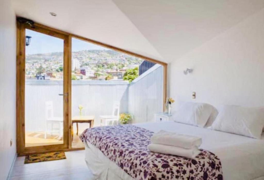 a bedroom with a bed and a large window at Escalera al Puerto Guest House in Valparaíso