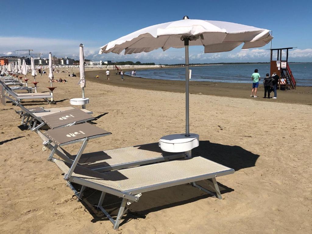 a row of beach chairs with an umbrella on the beach at Eco Hotel Cleofe in Caorle