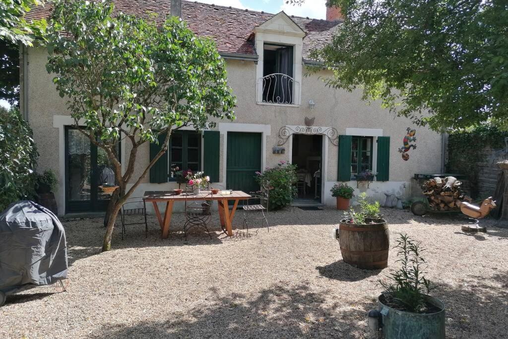 un patio con mesa y sillas frente a una casa en LE COTTAGE DES SABLONS près du zoo de Beauval, en Saint-Romain-sur-Cher