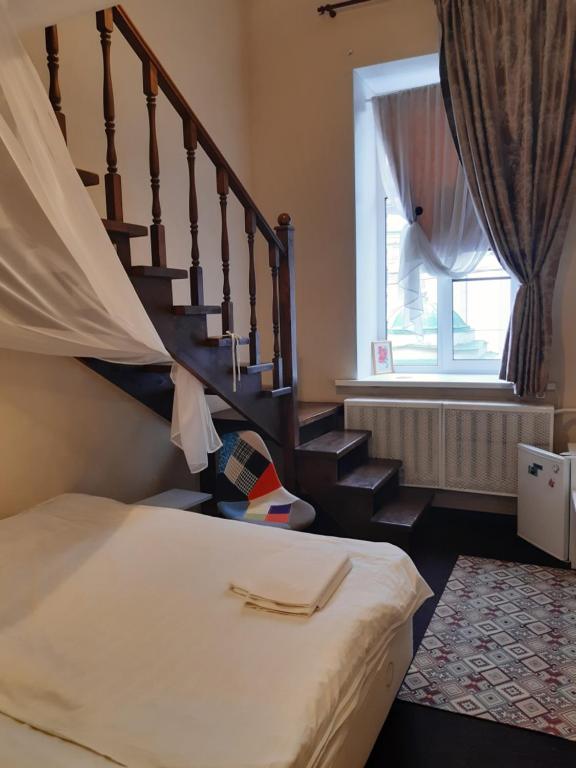 a bedroom with a bed and a stair case at Комнаты в Кузнечном переулке in Saint Petersburg