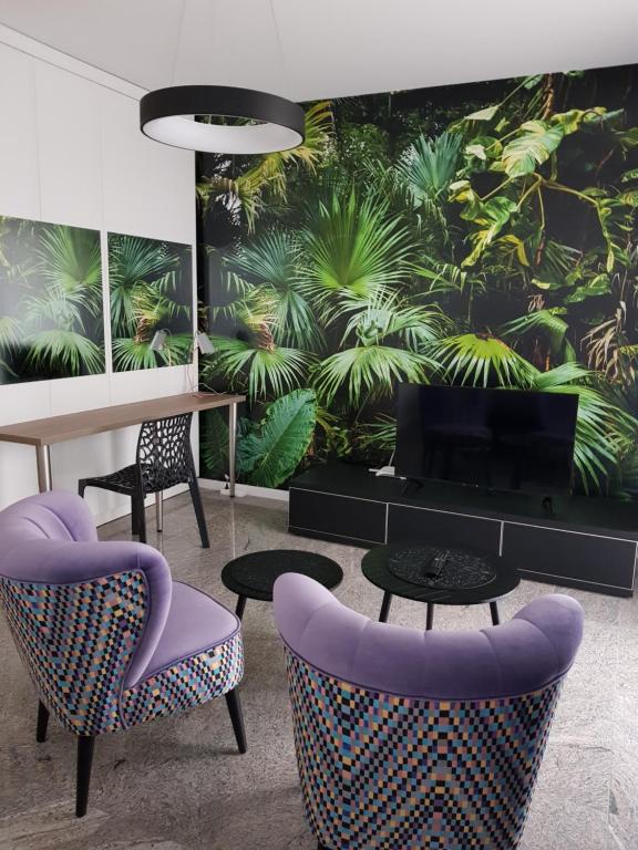 a dining room with purple chairs and a wall with plants at Roadway Silniczna z garażem podziemnym in Kielce