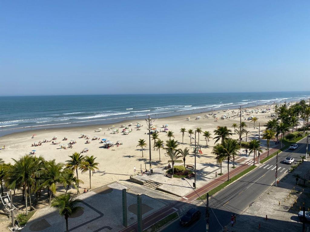 una spiaggia con persone e palme e l'oceano di Apartamento na Praia Grande - Aviação a Praia Grande