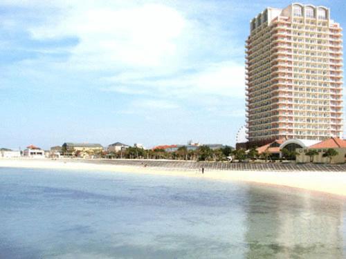 ein großes Gebäude an einem Strand neben dem Meer in der Unterkunft The Beach Tower Okinawa in Chatan
