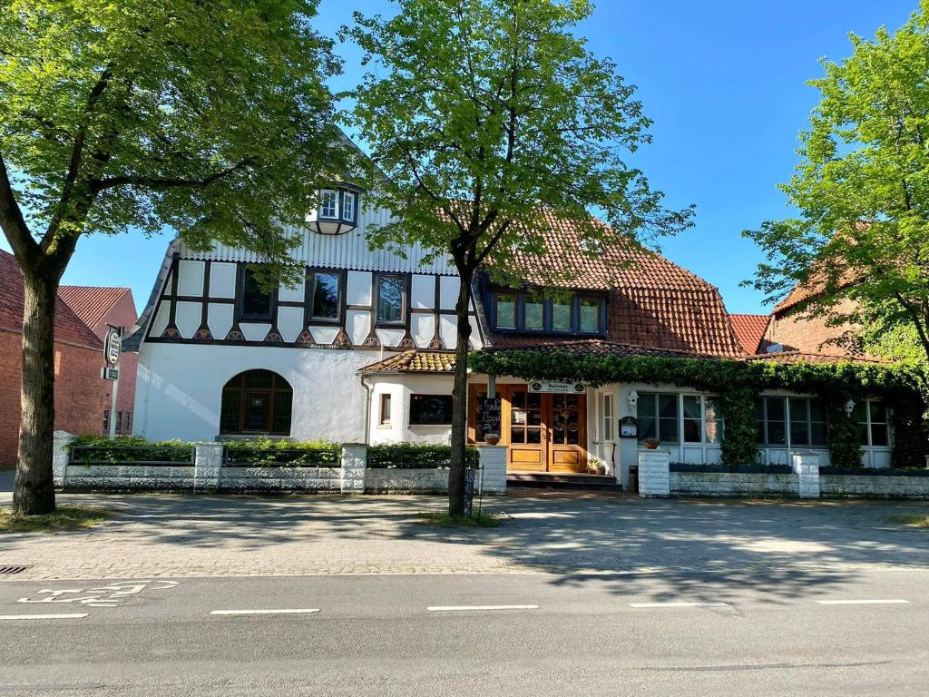 Una casa blanca con un árbol delante. en Landgasthof Voltmer, en Ramlingen