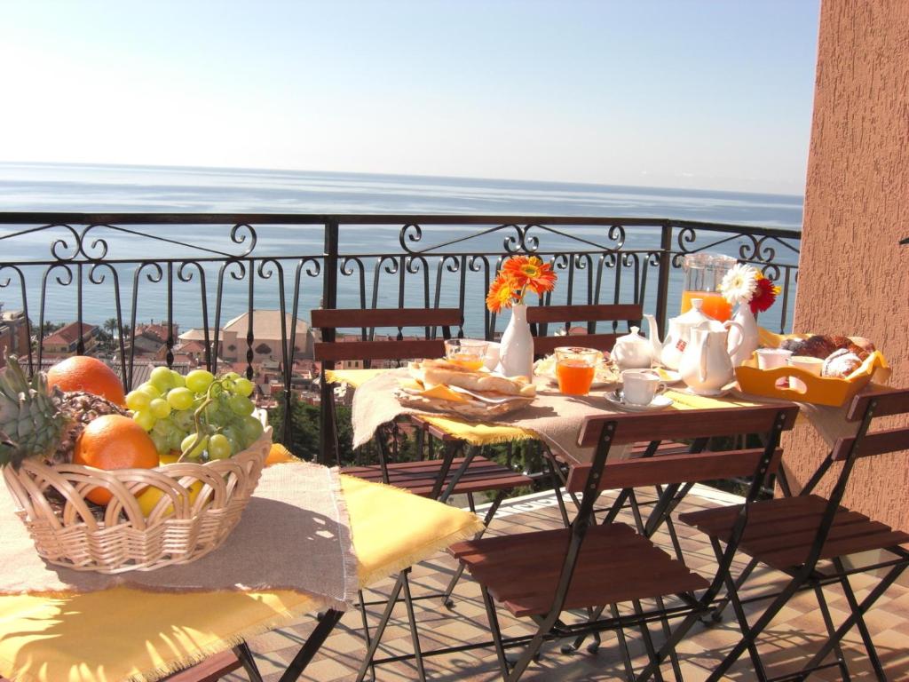 a table with food on a balcony with a view of the ocean at Pietra Preziosa Bed & Breakfast in Pietra Ligure