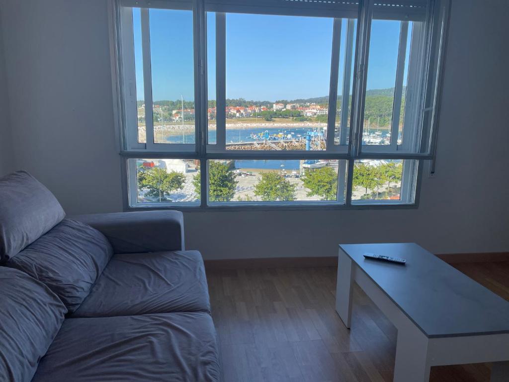 ein Wohnzimmer mit einem Sofa und einem großen Fenster in der Unterkunft Piso en Portonovo con vistas a la playa in Sanxenxo