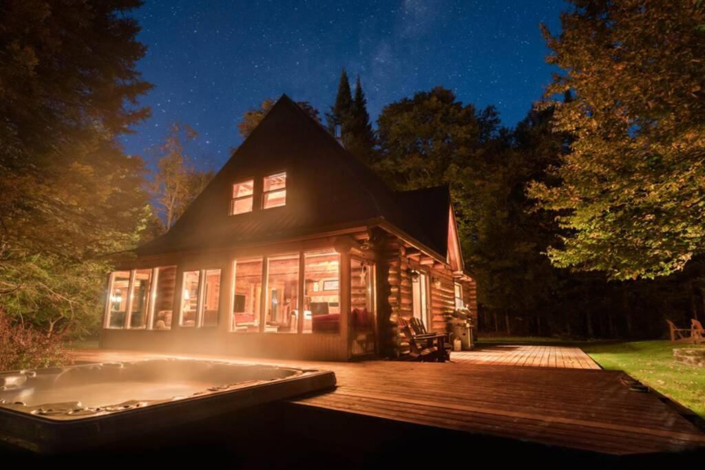 een huis met een terras en een hot tub bij The Beaver Lodge by Escapades Tremblant in Lac-Superieur