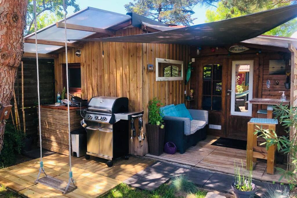 um pátio no quintal com um grelhador e uma casa em La cabane de Carol au coeur du bassin d'Arcachon em Le Teich