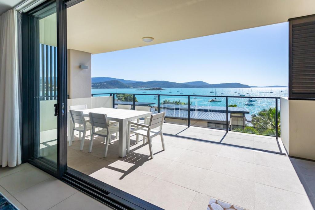 a balcony with a table and chairs and a view of the ocean at 3 Bedroom Ultimate Luxury Waterfront in Cannonvale