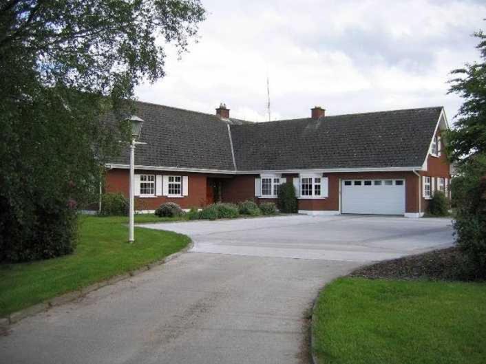 una casa roja con garaje blanco y entrada en Birchwood B&B, en Kells