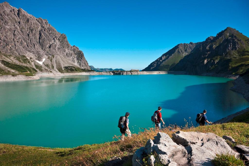 three people walking on a hill near a lake at Haus Kella-Egg in Brand