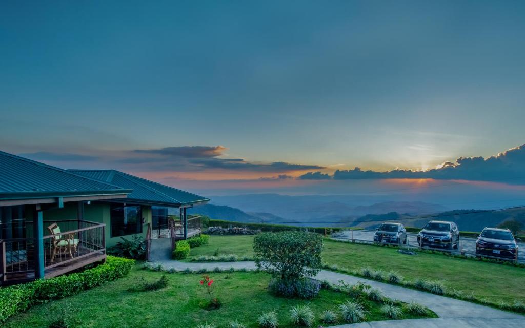 uma vista para uma casa com carros estacionados num campo em Hotel Trópico Monteverde em Monteverde