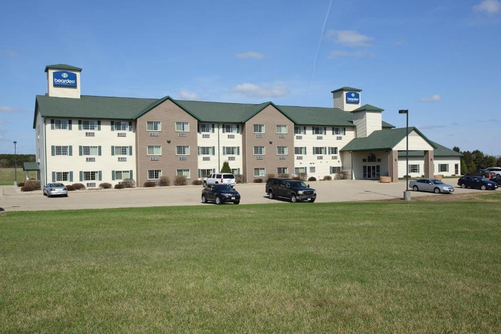 a large building with cars parked in a parking lot at Boarders Inn & Suites by Cobblestone Hotels - Shawano in Shawano