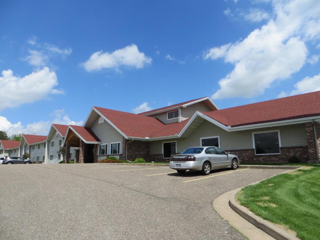 een huis met een auto geparkeerd op een parkeerplaats bij AmericInn by Wyndham Baldwin in Baldwin