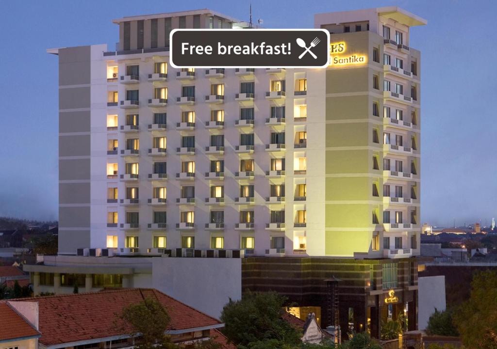 un gran edificio blanco con una señal de desayuno gratuita en Hotel Santika Pandegiling - Surabaya, en Surabaya