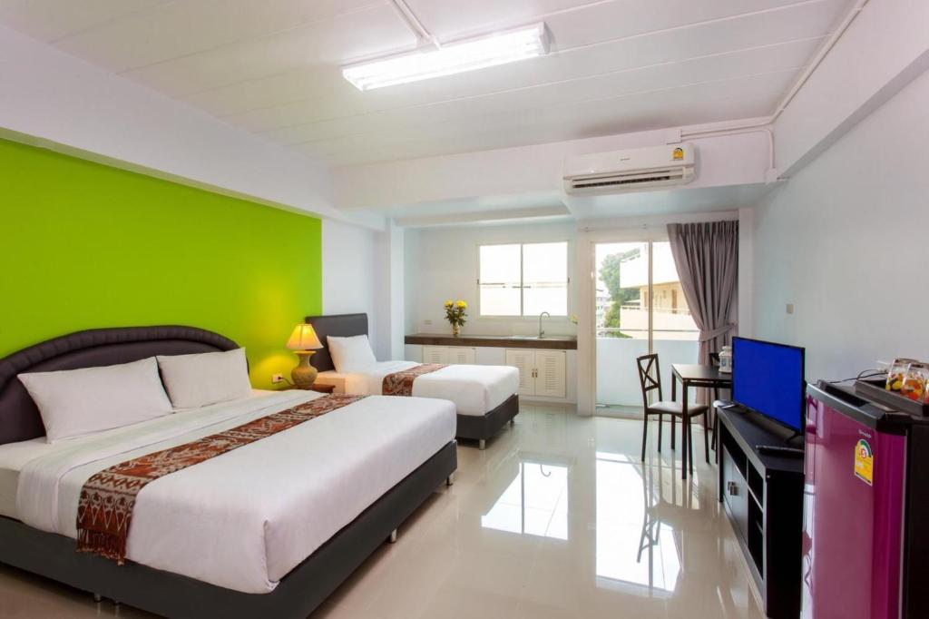 a bedroom with a large bed and a green wall at CW Mansion Phuket in Phuket Town