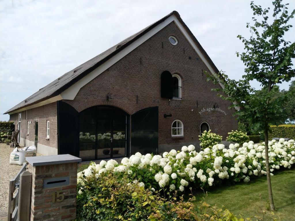 una gran iglesia de ladrillo con flores blancas delante de ella en B&B Agnetenhoeve, en Overasselt