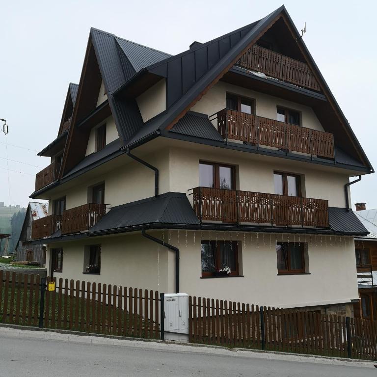 a house with a black roof and a fence at Janickowa Ostoja - Noclegi w Zakopanem in Zakopane