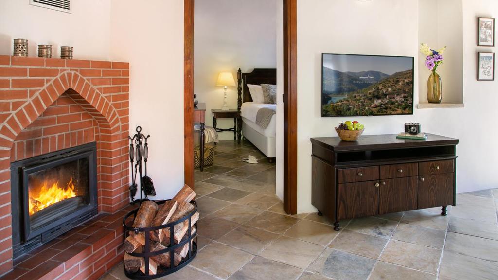 a living room with a brick fireplace and a bedroom at Casale Panayiotis in Kalopanayiotis
