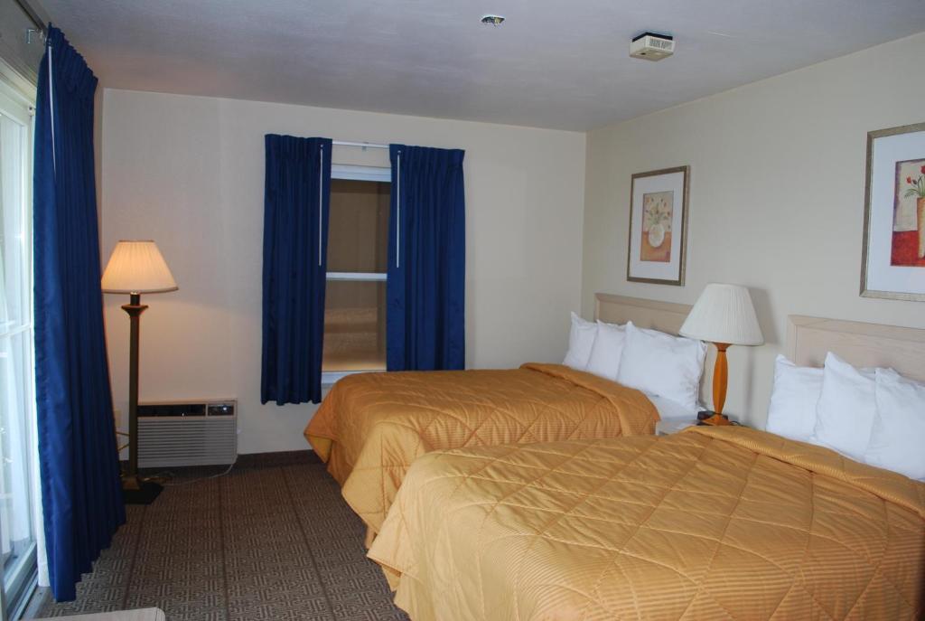 a hotel room with two beds and blue curtains at Clinton Inn & Suites in Port Clinton