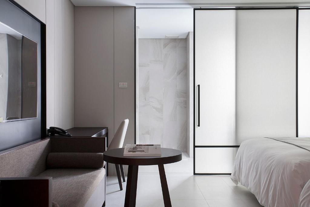 a bedroom with a bed and a table and a chair at Manho Hotel in Taichung