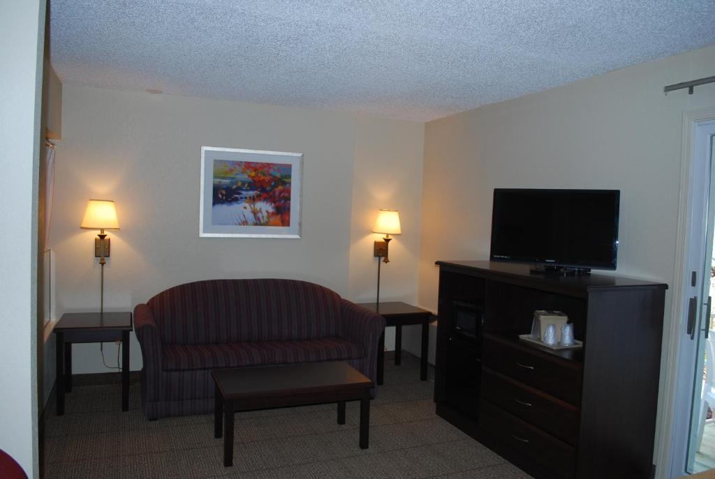 a living room with a chair and a flat screen tv at Clinton Inn & Suites in Port Clinton