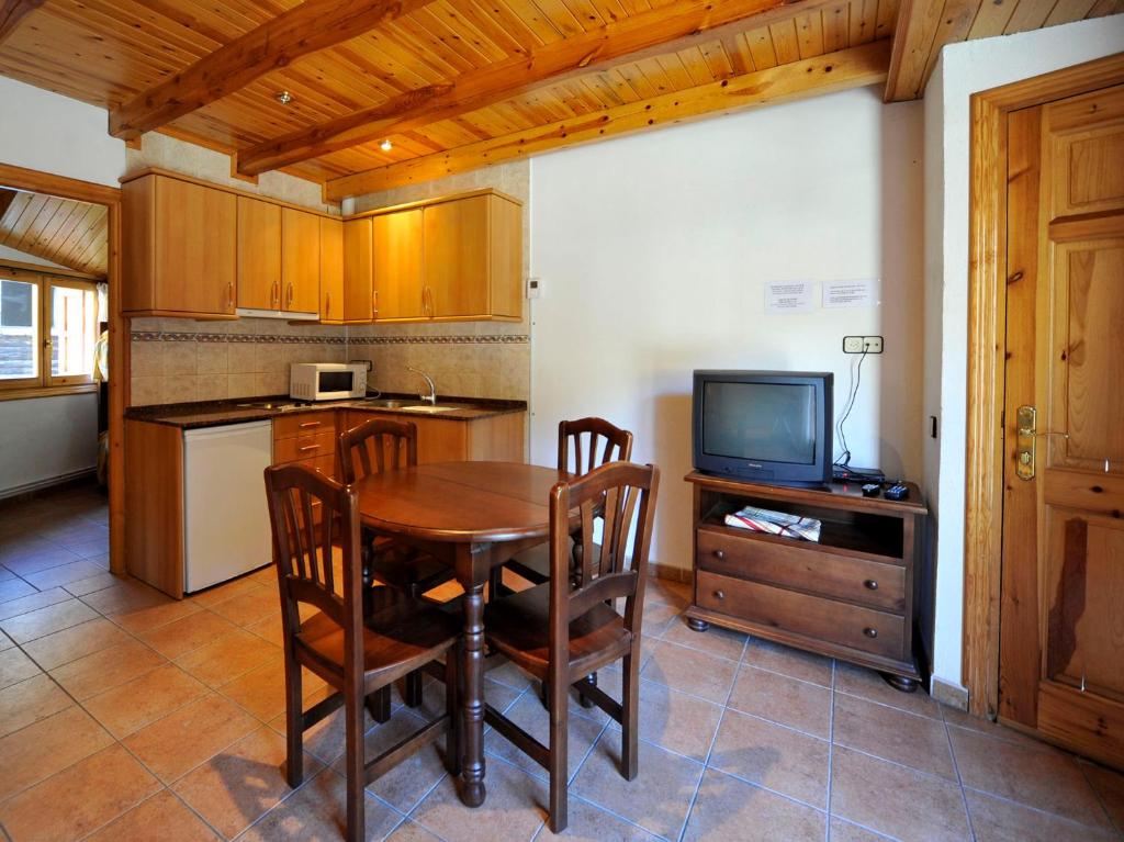 cocina con mesa de madera y TV en Apartament L'àtic, en Espot