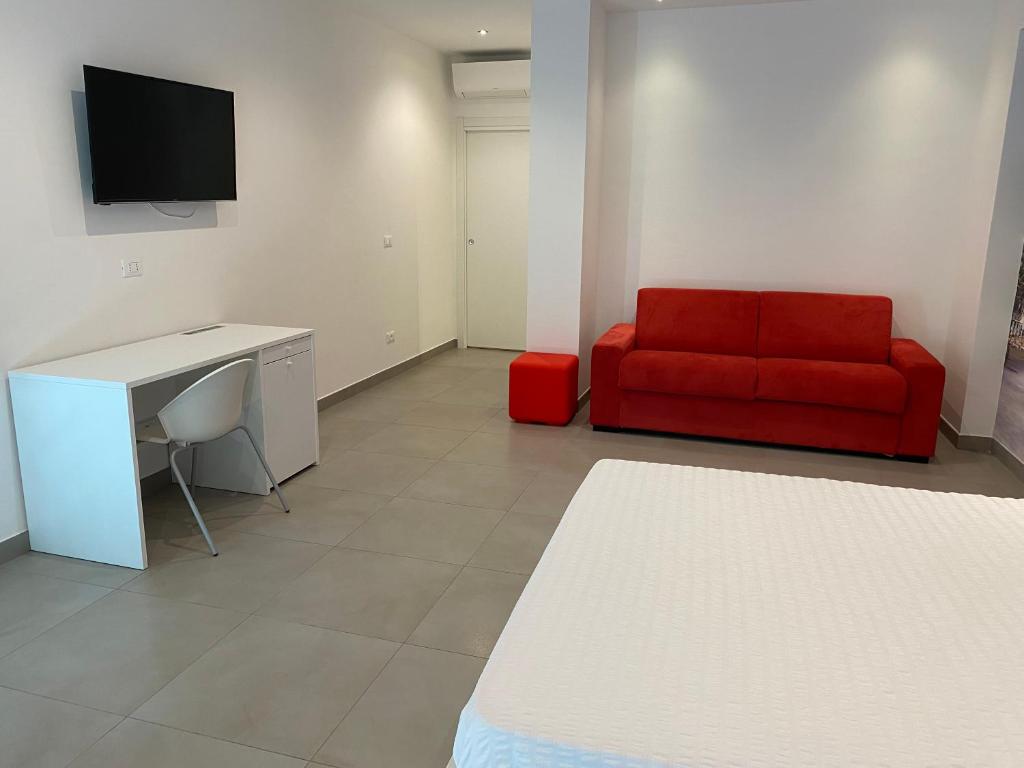 a living room with a red couch and a desk at Torre del mare Rooms in Bergeggi