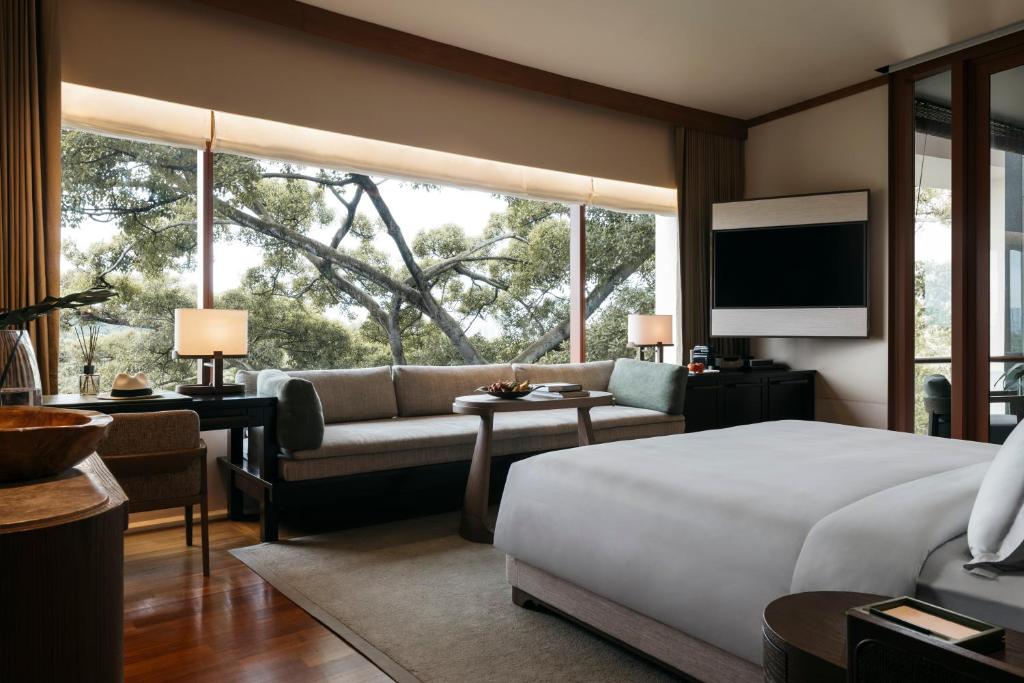 a bedroom with a bed and a couch and a large window at Capella Singapore in Singapore
