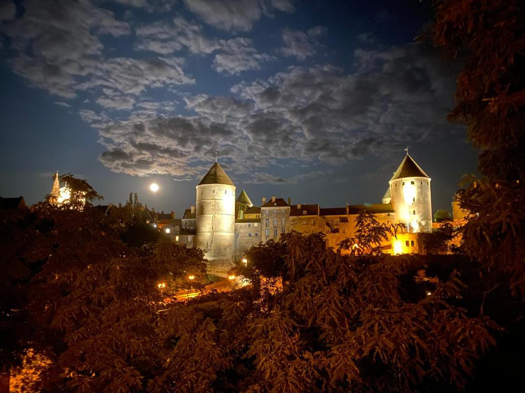 un château allumé la nuit dans l'établissement Bâtisse du pont Pinard et son granit rose, à Semur-en-Auxois