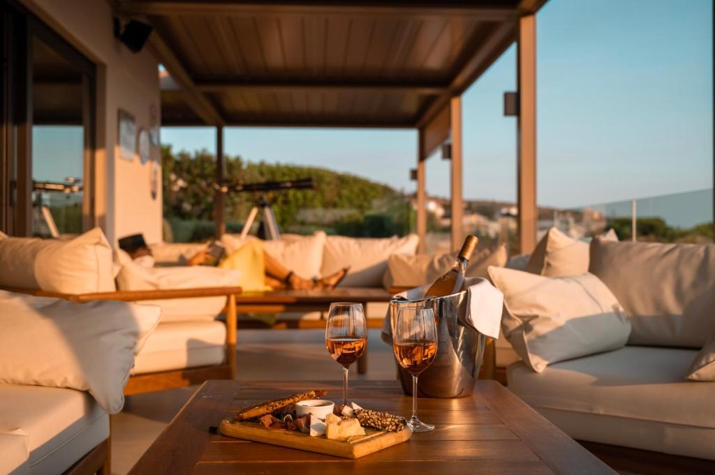 a living room with two glasses of wine on a table at Somewhere Vouliagmeni in Athens