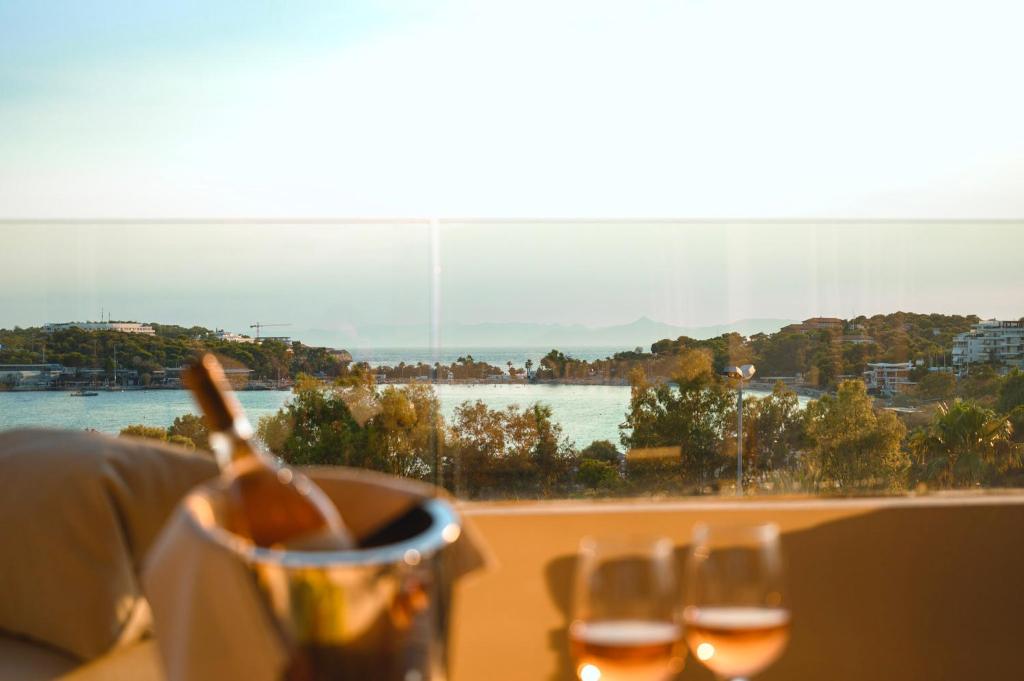 a table with wine glasses and a view of the water at Somewhere Vouliagmeni in Athens