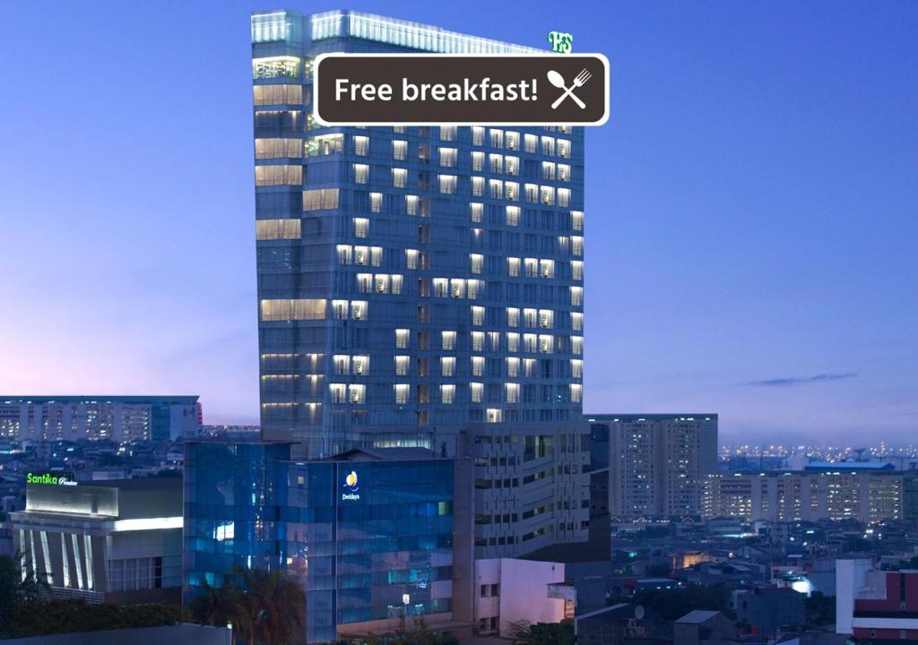 um edifício alto com um sinal de pequeno-almoço gratuito em Hotel Santika Premiere Hayam Wuruk Jakarta em Jacarta