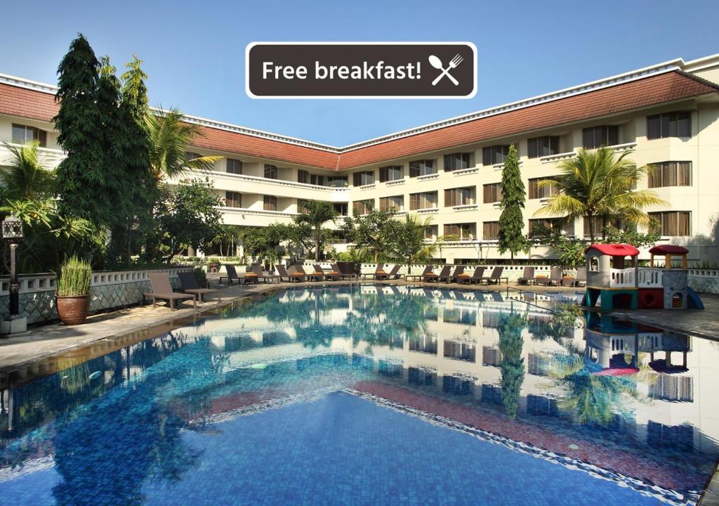 a swimming pool in front of a hotel at Hotel Santika Premiere Jogja in Yogyakarta