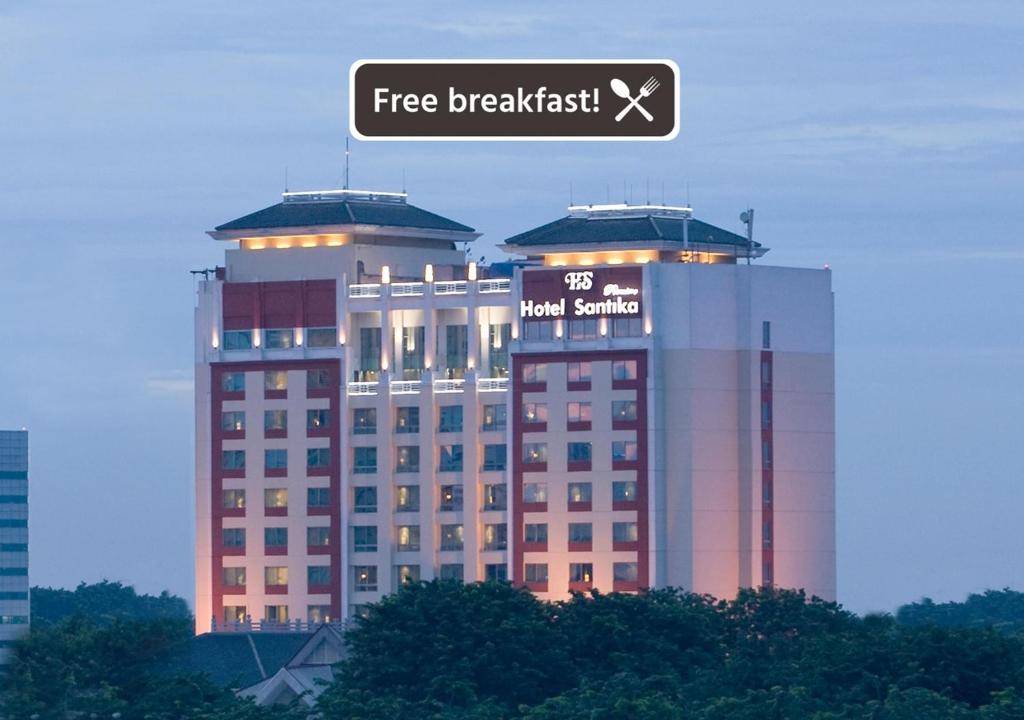 a large building with a sign on top of it at Hotel Santika Premiere Slipi Jakarta in Jakarta