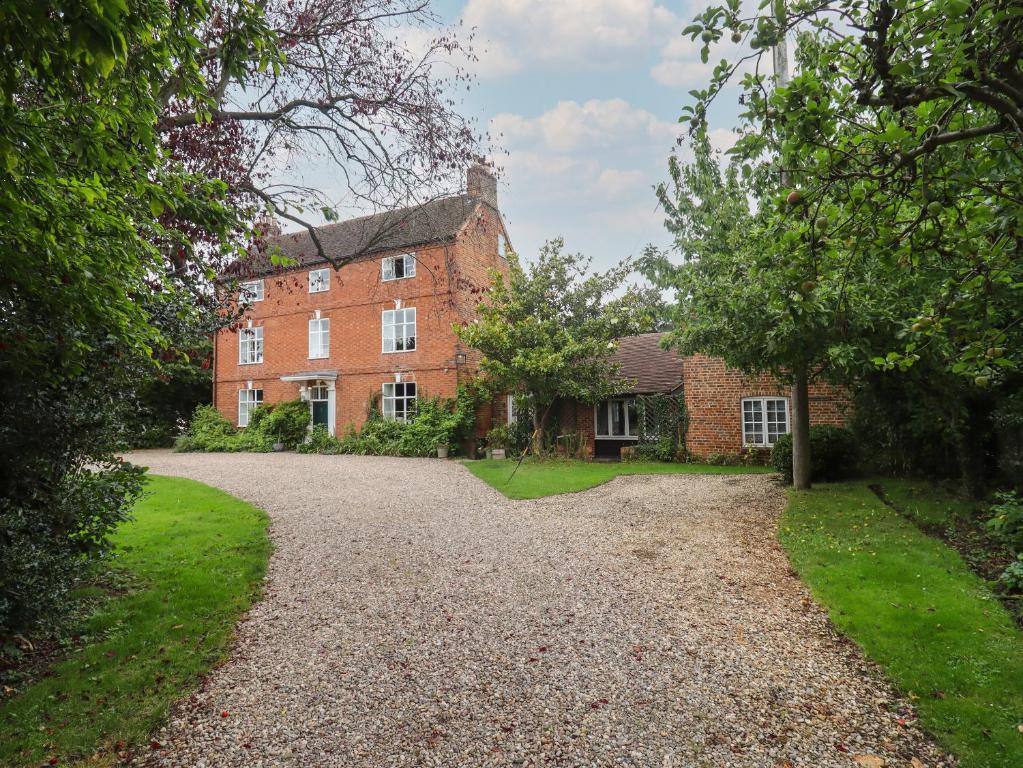 una gran casa de ladrillo rojo con entrada de grava en The Coach House Apartment en Tewkesbury