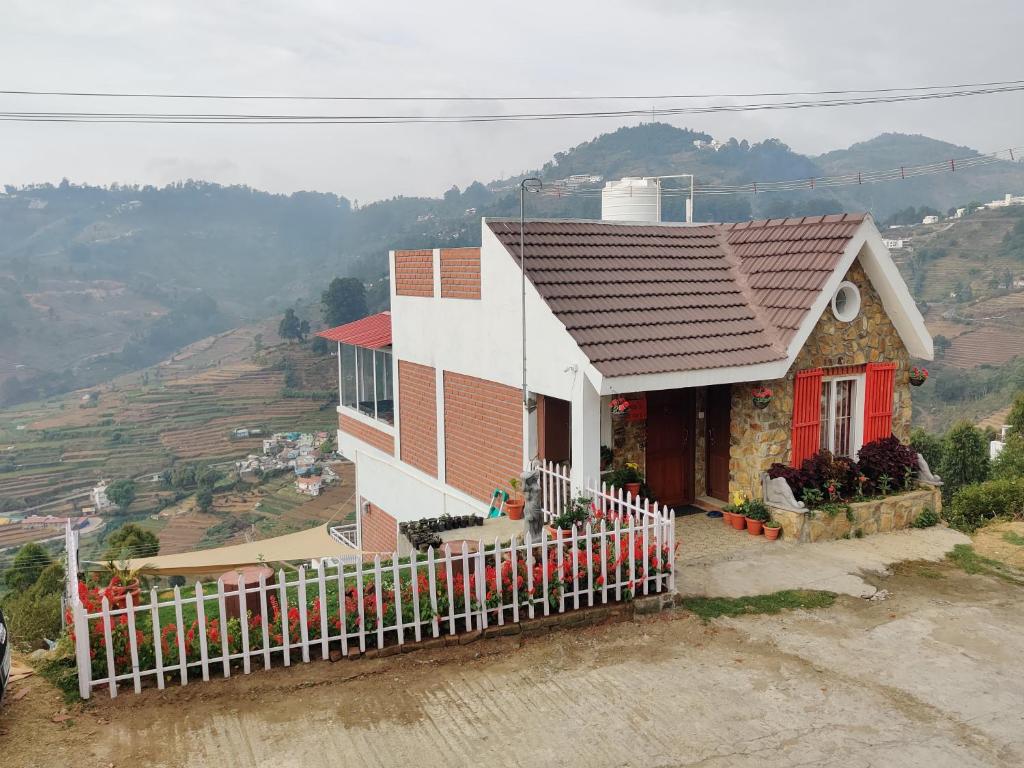 uma pequena casa com uma cerca em frente em Sipa's HideOut em Kodaikanal