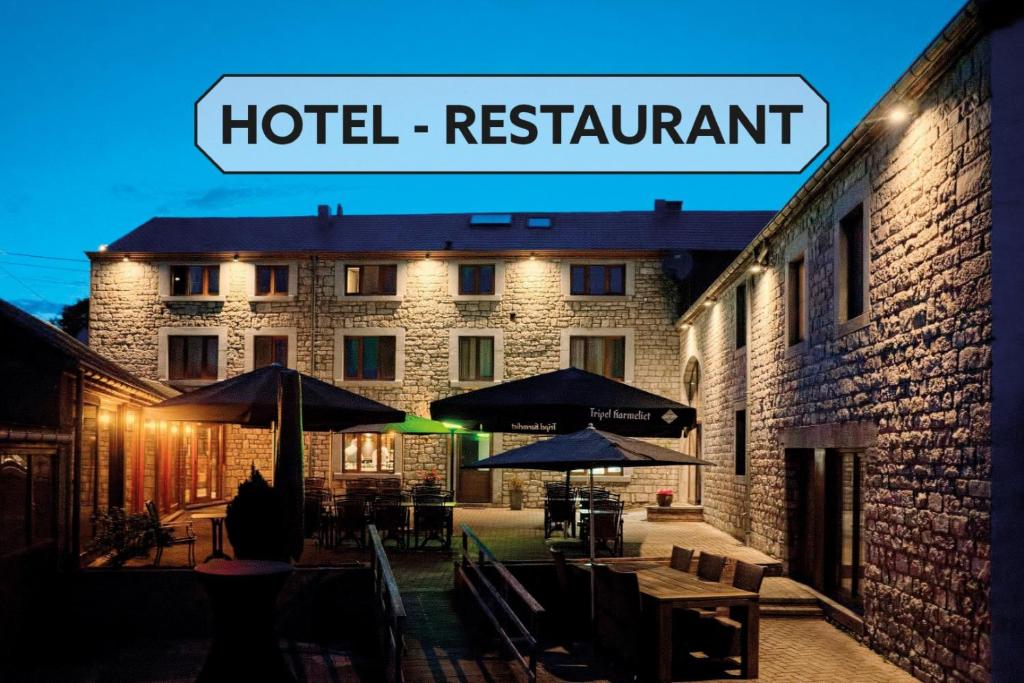 a hotel restaurant with tables and umbrellas in front of a building at Hotel & Restaurant Maison Pal'Ange in Durbuy