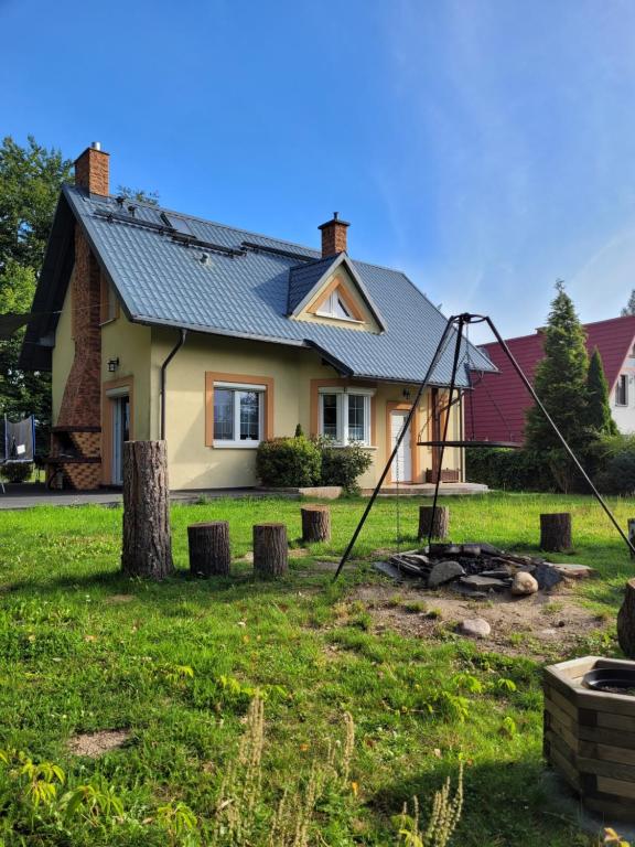 a house with a metal roof on top of a yard at DOM NA KASZUBACH, SAUNA i BALIA in Nowe Czaple